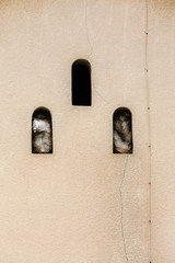 trio of arched windows reflecting mysterious objects in beige wall