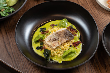 Cod fillet baked with avocado puree and israeli ptitim on wooden table