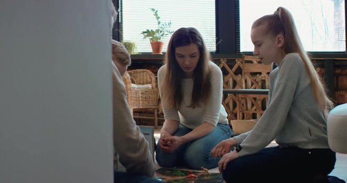 Family - father, mother and two kids playing a board game together. Stay home, quarantine. Board game is custom made for the shot. RED Dragon