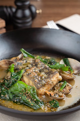 Close up of marinated fish with stewed scallops and spinach, dressed with hazelnut sauce