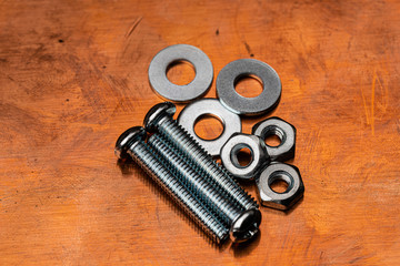 A Macro shot of several small stainless steel bolts, washers and nuts on a dirty and worn copper...