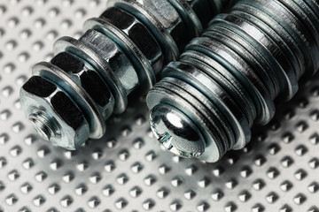 cool blue toned macro of small bolts with nuts and washers on an industrial steel surface.  Strong Contrast