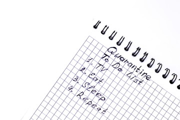 Fototapeta premium Humorous business concept into period of quarantine for coronavirus. To-do list for period of self-isolation including eating, sleeping, watch TV writing on paper sheet of notepad on white background