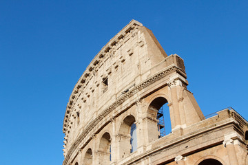Fototapeta premium The exterior facade of the Colosseum or Coliseum with the arches against blue clear sky in Rome, Italy