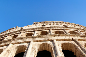 Obraz premium The exterior facade of the Colosseum or Coliseum with the arches against blue clear sky in Rome, Italy