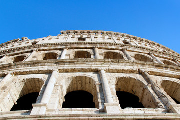 Obraz premium The exterior facade of the Colosseum or Coliseum with the arches against blue clear sky in Rome, Italy