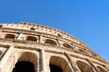 Obraz premium The exterior facade of the Colosseum or Coliseum with the arches against blue clear sky in Rome, Italy