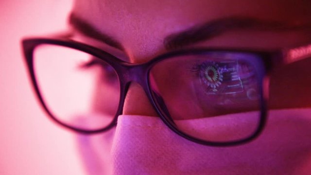 Scientist woman studying data of Coronavirus outbreak virus model displayed on laptop screen reflected on glasses