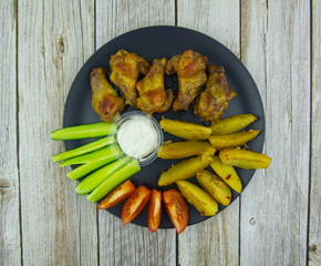 Fried chicken wings and potatoes with vegetables and sauce