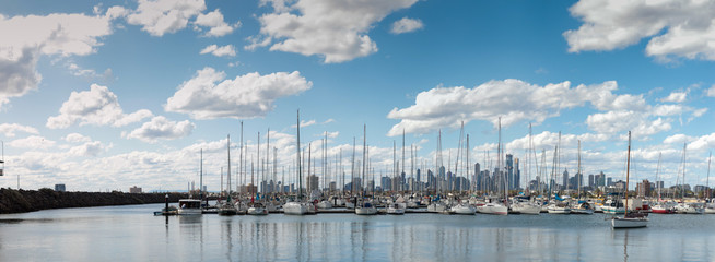 Panoramic of the city of Melbourne against a sunny blue sky seen from St Kilda pier looking through the masts of yachts in the bay, Melbourne, Victoria, Australia