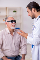 Old blind man visiting young male doctor