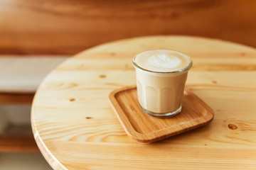 A beautiful cup of cappuccino with latte art in the wooden space background. Trendy toning.