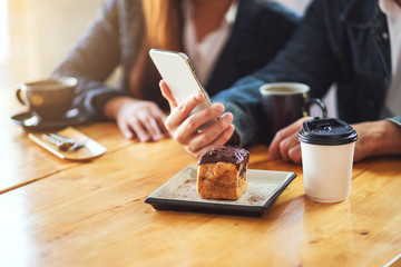 A group of young asian people using and looking at the same mobile phone together in cafe