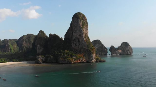 Sunset ocean white sand tropical beach at railey phra nang beach thailand drone footage. Limestone cliffs rocks in the andaman sea torquiose vacation with long tail boats.