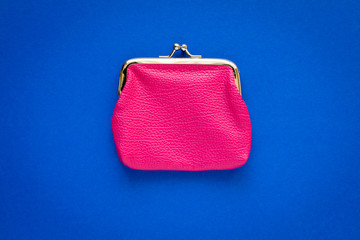 Fashionable pink wallet on a blue background. Close up.