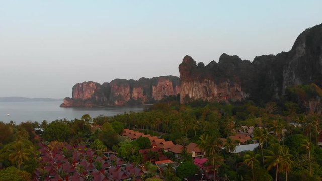 Long tail boats on the water at sunset tropical railey phra nang beach thailand drone footage. Limestone cliffs rocks in the andaman sea relaxing sunrise.
