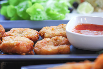 Shrimp nuggets with red sweet sauce on black plate table closeup background