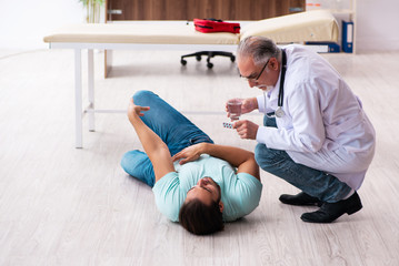 Old experienced doctor and young male patient lying on the floor