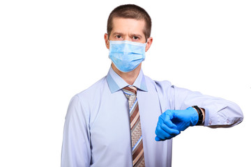 Male doctor wearing medical mask, rubber gloves, looks at watch, pointing to time