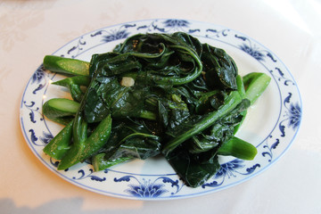 Stir fried Chinese broccoli (Gai lan) with garlic on a plate in a Chinese Restaurant