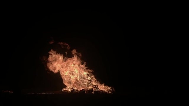 Large bonfire fire with huge flames burning upwards into the sky.