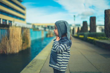 Fototapeta premium Little preschooler standing by artificial pond in the city