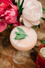 A close up of a creamy light pink cocktail in a beautiful glassware on a rustic background