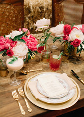 A beautifully decored table with white and pink florals and vintage tableware ready a celebration to start