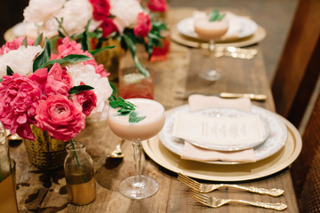 A table setting ready for a celebration decorated with pink and white florals and showcasing a signiture creamy cocktail