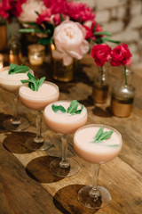 Light pink creamy alcoholic cocktails garnished with mint on a rustic surface