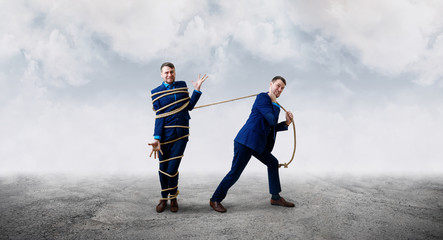 Angry businessman pulls tied himself with a rope.