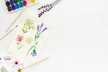 Drawing flowers with watercolor paintis on white background top-down frame copy space