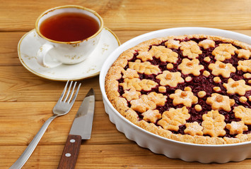 Homemade cherry pie crostata and cup of tea on white wooden table. Angle view.