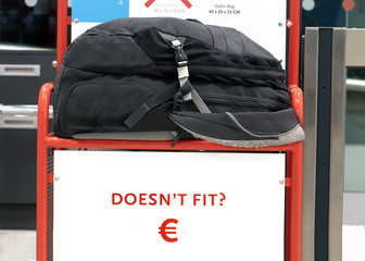 The large backpack lying on a control cage for measure size of carry on luggage. Checking baggage...