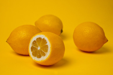 Ripe and juicy lemons shot on a yellow background. Background for vitamins and fruits.