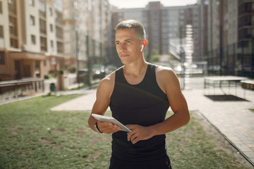 Man with a tablet. Guy in a sports clothes. Male in a summer park