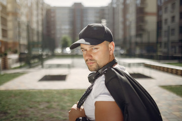 Man with a headphones. Guy in a sports clothes. Male in a summer park with backpack