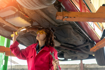 Woman Mechanic Examining Under the Car at the Repair Garage.