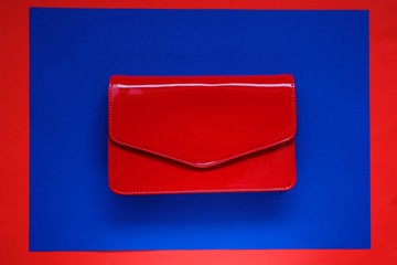 red handbag.  clutch. Women leather handbag.Fashion accessory. red patent leather clutch on a bright blue and red background.Fashionable  women's  hand bag in bright colors.