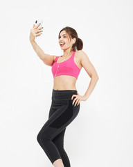 Fototapeta na wymiar portrait of a smiling fitness woman with smartphone. Selfie time.