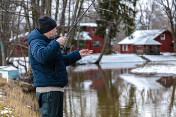 A man with a fishing rod on the river. Winter fishing. Finland March 2020