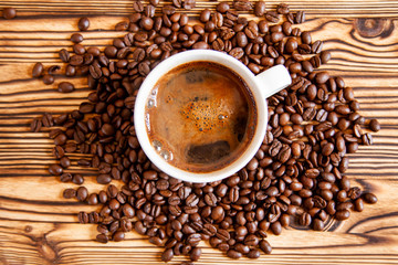 White cup of coffee stands on coffee beans