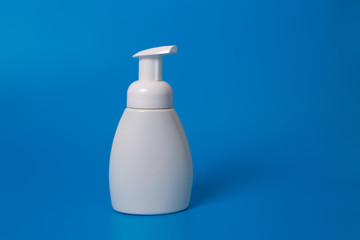White bottle of liquid soap on a blue background