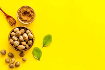 Nutmeg - spices in powder and whole nuts - on yellow background top-down copy space