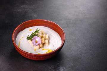 Delicious beautiful mushroom soup in a brown plate with a wooden spoon