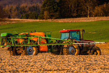agricultural tractor in the spring field while performing chemical spraying