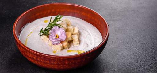 Delicious beautiful mushroom soup in a brown plate with a wooden spoon