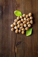 Nutmeg - whole nuts near leves - on wooden background top-down
