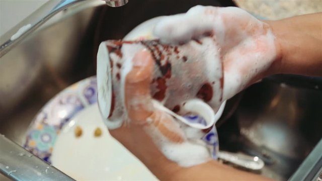 Mug washed over sink with dirty dishes. Handheld shot. Close up.