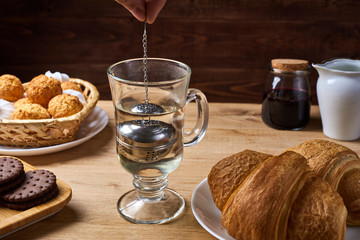 Hot tea put on table, drink breakfast in the morning day, breakfast with tea strainer and sweets on wooden table